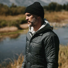 fit model wearing The Waffle Beanie in Coal Merino in front of a stream