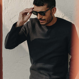 Fit model wearing The Weekend Crewneck in Navy Boiled Wool while taking off his sunglasses
