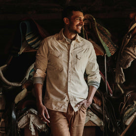 fit model wearing the shirt in a barn in front of horse saddles from the front