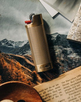 editorial image of The Lighter Sleeve in Brass on top of magazines, Accessories by Taylor Stitch