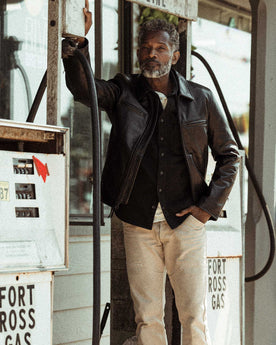 fit model posing against a car in The Moto Jacket in Black Steerhide, Outerwear by Taylor Stitch