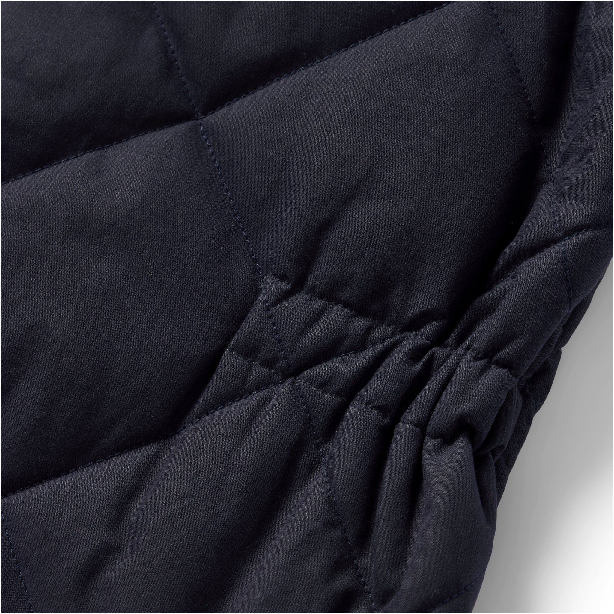 material shot of the cinched detail on The Quilted Bomber Vest in Navy Dry Wax, Outerwear by Taylor Stitch