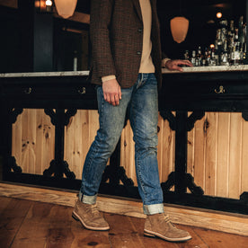 fit model leaning against a chair wearing The Rambler Chukka in Mushroom Suede