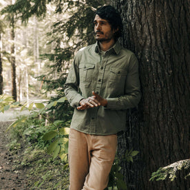 fit model leaning against a tree wearing The Saddler Shirt in Washed Olive