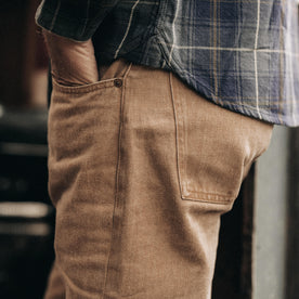 fit model with his hand in his pocket wearing The Slim All Day Pant in Washed Tobacco Selvage