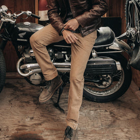 fit model sitting on a motorcycle wearing The Slim All Day Pant in Washed Tobacco Selvage