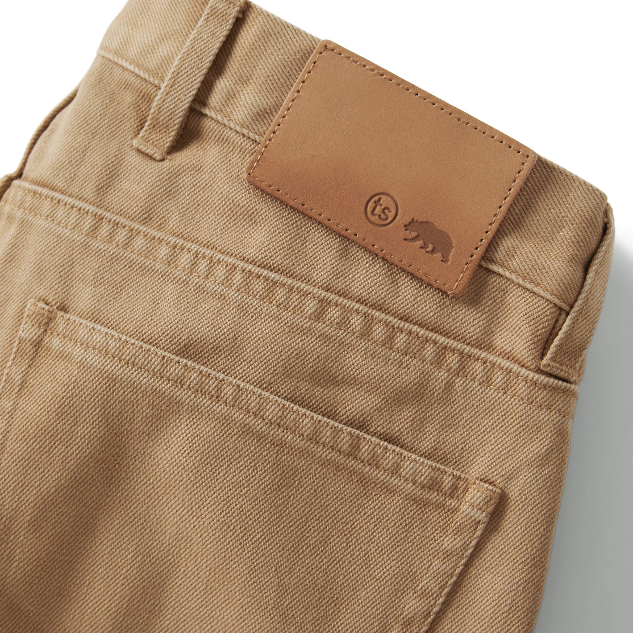 material shot of the back leather flap on The Slim All Day Pant in Washed Tobacco Selvage, Bottoms by Taylor Stitch