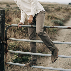 fit model climbing over a fence in The Slim All Day Pant in Washed Walnut Selvage