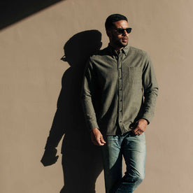 our fit model wearing The Jack in Olive Slub Chambray—against a wall, looking right