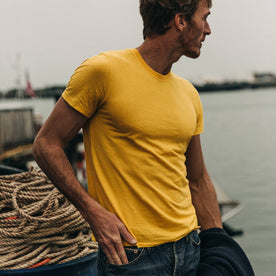 fit model wearing The Cotton Hemp Tee in Gold, standing by dock