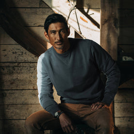 fit model wearing The Crewneck in Sea Green Terry, in boathouse, sitting
