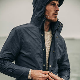 fit model wearing The Dalton Jacket in Navy on a ferry, looking right, zipping jacket