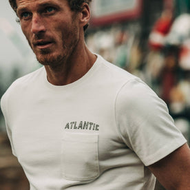 fit model wearing The Heavy Bag Tee in Atlantic, cropped shot of chest near water