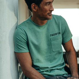 fit model rocking The Heavy Bag Tee in Pacific, sitting on porch, looking right