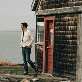 fit model wearing The Long Haul Jacket in Natural Organic Selvage, standing near red door