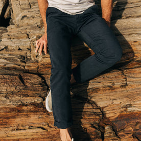 fit model wearing The Morse Pant in Navy Slub Linen, sitting on rocks