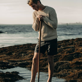 fit model wearing The Morse Short in Navy Slub Linen, leaning on oar