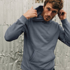 fit model wearing The Shackleton Hoodie in Ocean, looking into camera, playing with hood