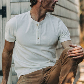 fit model wearing The Short Sleeve Heavy Bag Henley in Natural, sitting, with chore pants on