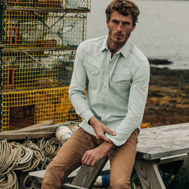 fit model wearing The Western Shirt in Washed Selvage Chambray, sitting on bench