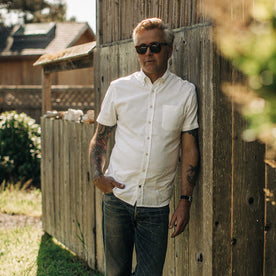 our fit model wearing The Short Sleeve Jack in Washed White Oxford outside on a fence