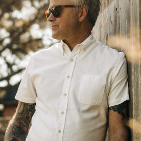 our fit model wearing The Short Sleeve Jack in Washed White Oxford outside on a fence, looking right
