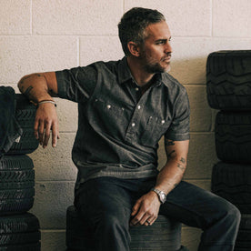 our fit model wearing The Short Sleeve Popover in Charcoal Chambray—sitting in the garage