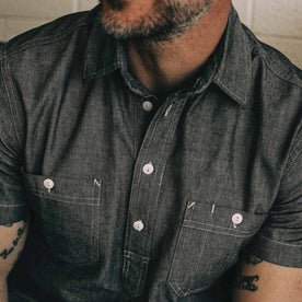 our fit model wearing The Short Sleeve Popover in Charcoal Chambray—sitting in the garage, cropped shot