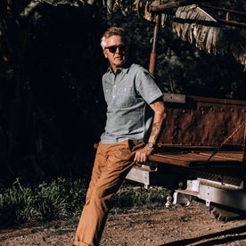 our fit model wearing The Short Sleeve Popover in Blue Chambray—looking left against a truck