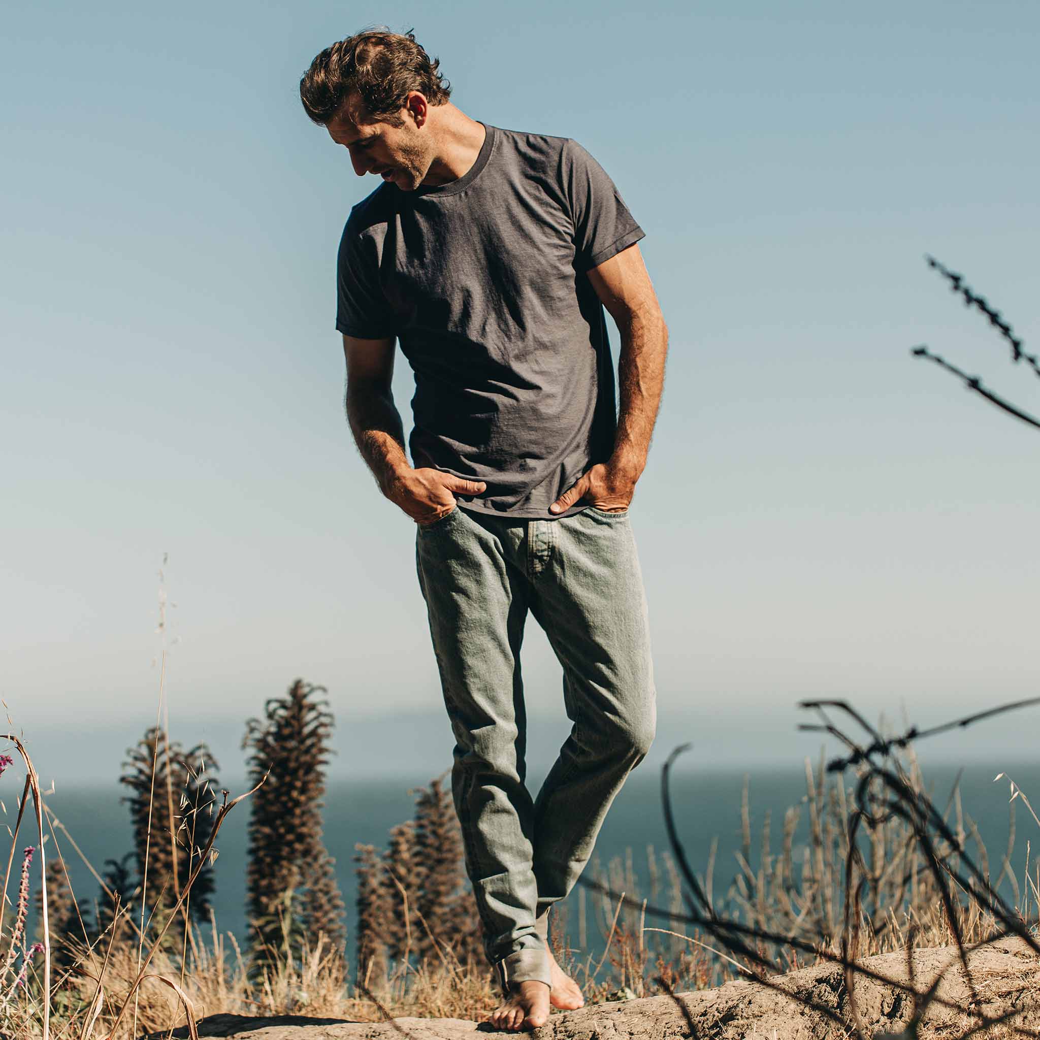our fit model wearing The Standard Issue Tee in Navy Hemp—outside on the beach walking, Knits by Taylor Stitch