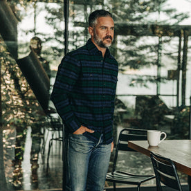 our fit model wearing The Yosemite Shirt in Blackwatch Plaid—drinking coffee at a cabin