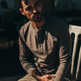 fit model wearing The Heavy Bag Henley in Espresso, sitting, playing with sleeve