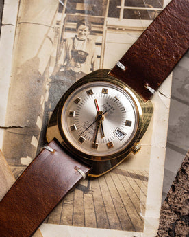 flatlay of the 1975 Timex Electric Dynabeat Time Zone, on a background of vintage photos, Accessories by Taylor Stitch