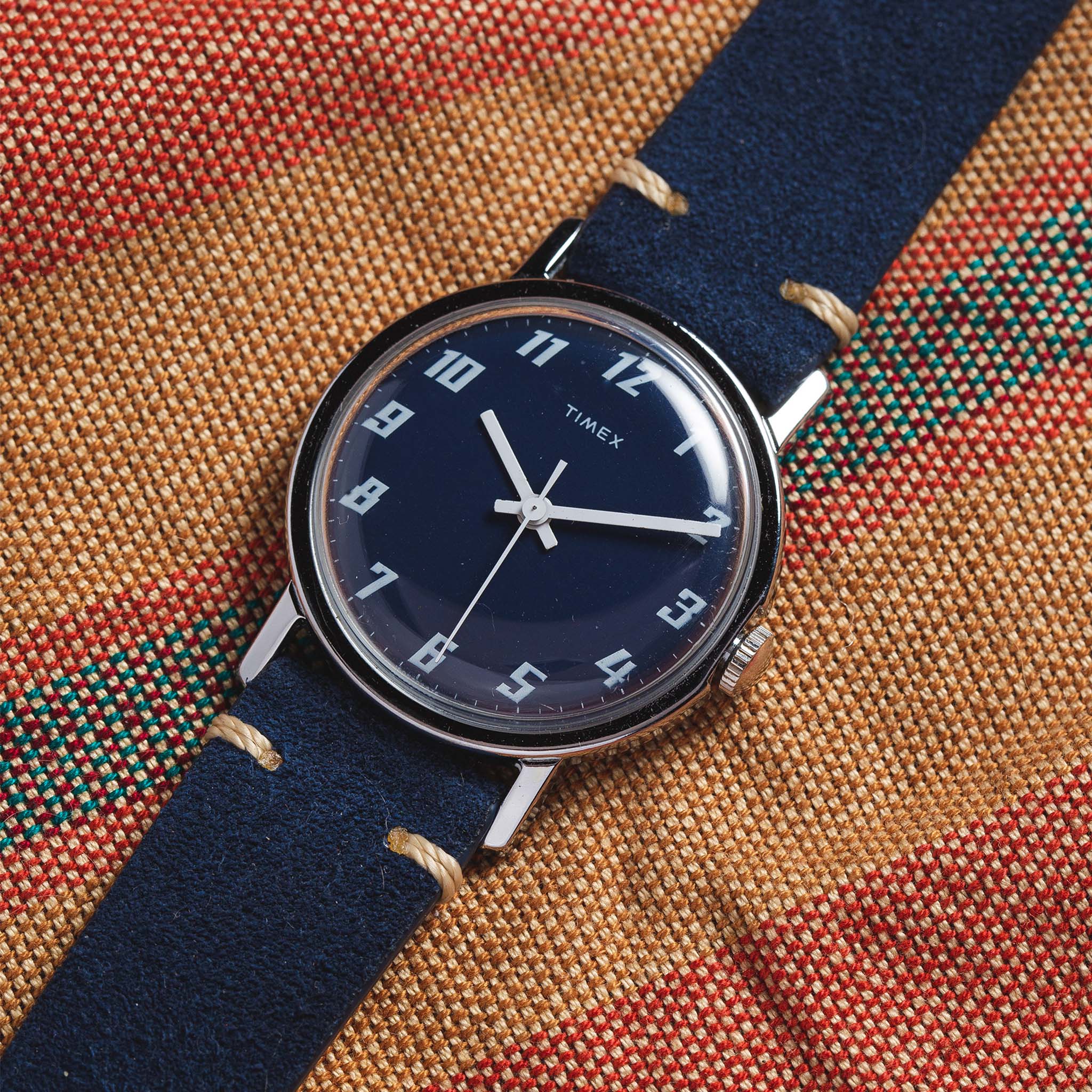 flatlay of the 1976 Timex Mercury Blue, on a striped background, Accessories by Taylor Stitch