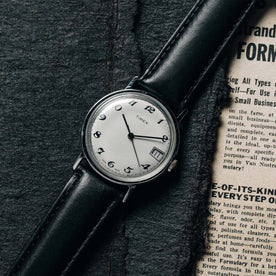 flatlay of the 1978 Timex Mercury, shown on a newspaper, Accessories by Taylor Stitch