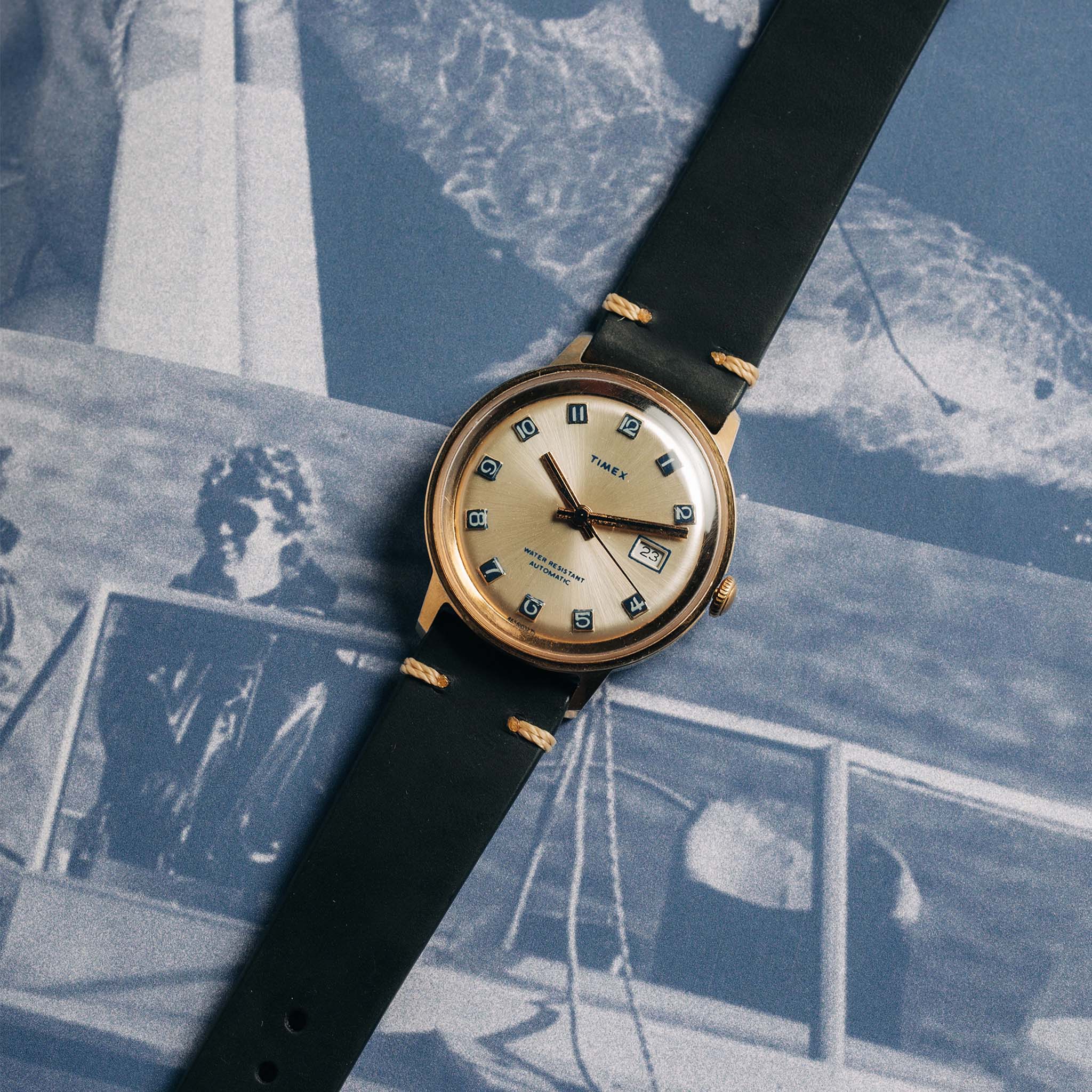 flatlay of the 1975 Timex Viscount against old photographs, Accessories by Taylor Stitch