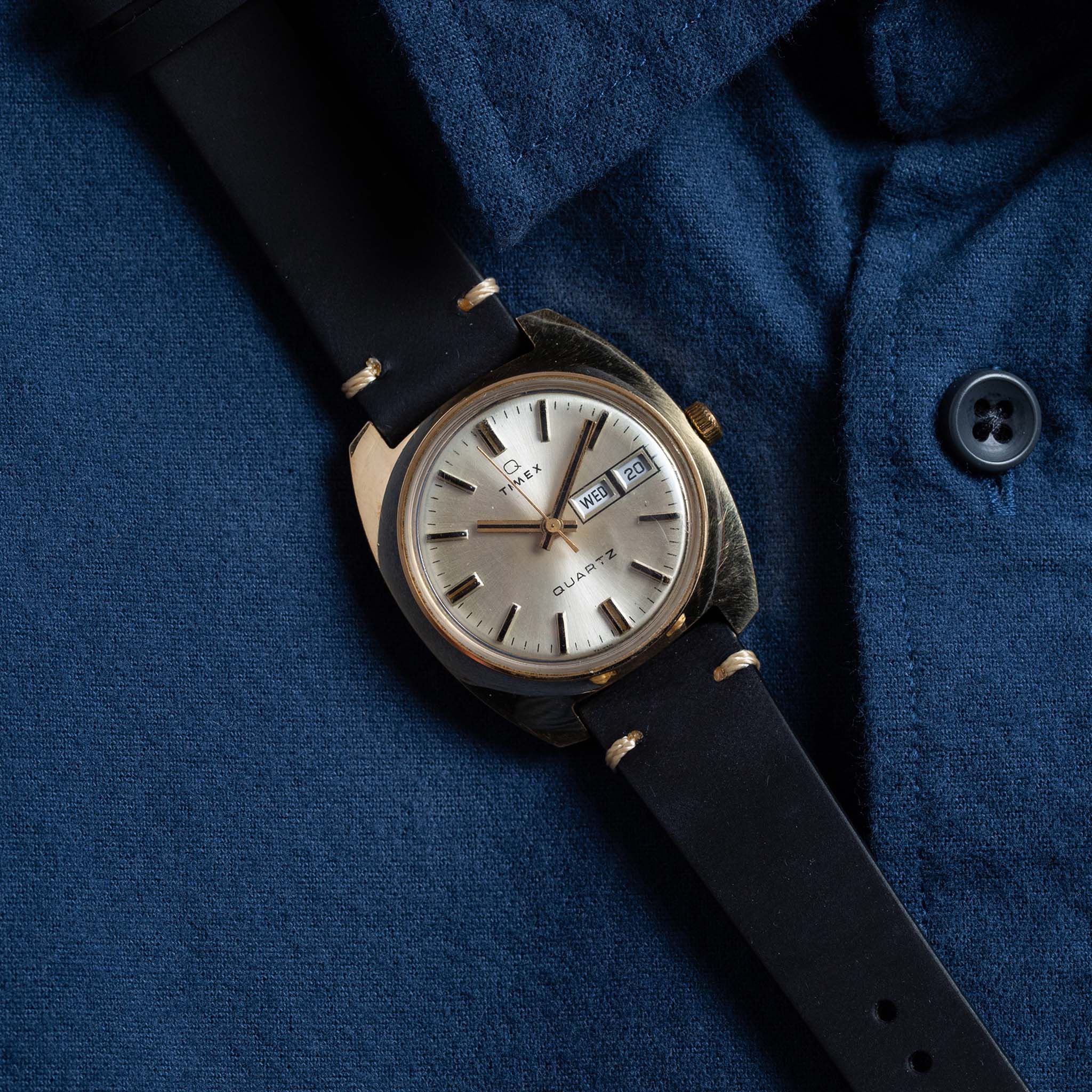 flatlay of the 1978 Timex Q Quartz against a blue shirt, Accessories by Taylor Stitch