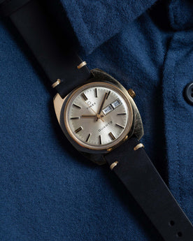 flatlay of the 1978 Timex Q Quartz against a blue shirt, Accessories by Taylor Stitch