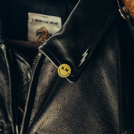 material shot of The All Smiles Enamel Pin on jacket