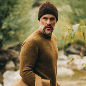 our fit model wearing The Beanie in Chocolate Baby Yak—walking near creek