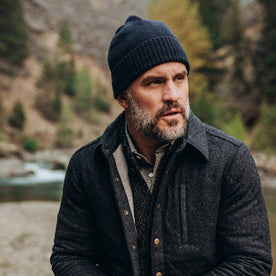 our fit model wearing The Beanie in Navy Baby Yak—sitting near creek