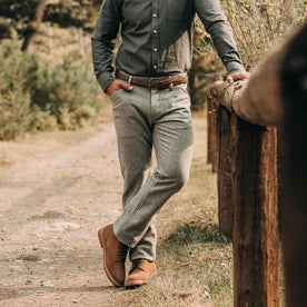 fit model wearing The Camp Pant in Heather Grey Wool—hand on wood fence