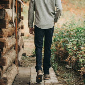 our fit model wearing The Camp Pant in Navy Donegal Herringbone—standing near shed, walking away from camera