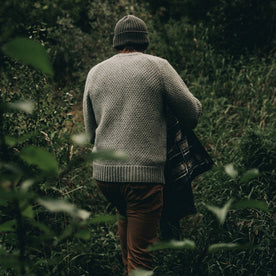 fit model wearing The Fisherman Sweater in Heather Ash, walking in brush