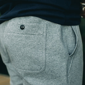 our fit model wearing The Heavy Bag Pant in Heather Grey Fleece closeup of back right buttoned pocket
