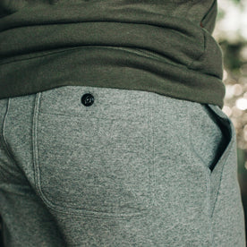 our fit model wearing The Heavy Bag Short in Heather Grey Fleece from the back with right side button pocket visible