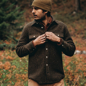 our fit model wearing The Leeward Shirt in Olive Donegal playing with buttons on placket in wildflower field 