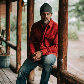 our fit model wearing The Maritime Shirt Jacket in Clifford Red—sitting, hands clasped