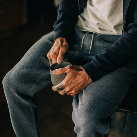 fit model wearing The Après Pant in Charcoal Waffle, sitting, holding coffee