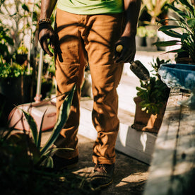 fit model in garden wearing The Carpenter Pant in Cedar Boss Duck